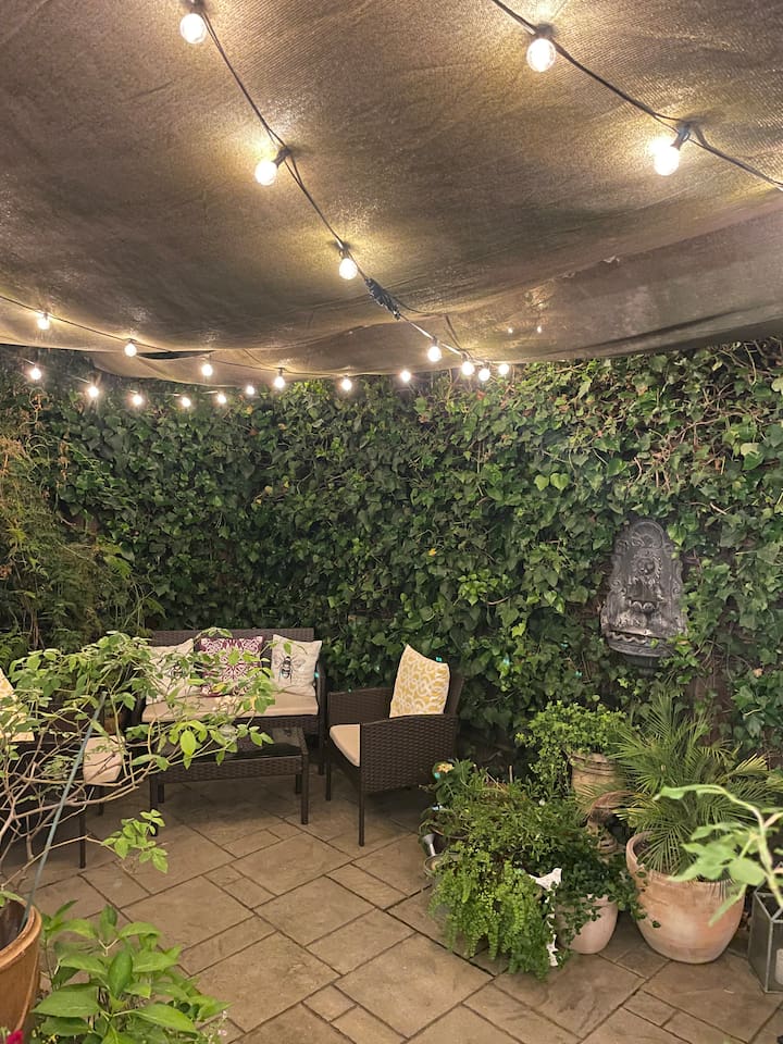 Peaceful backyard with warm string lights and fountains, perfect for relaxing in the evening.