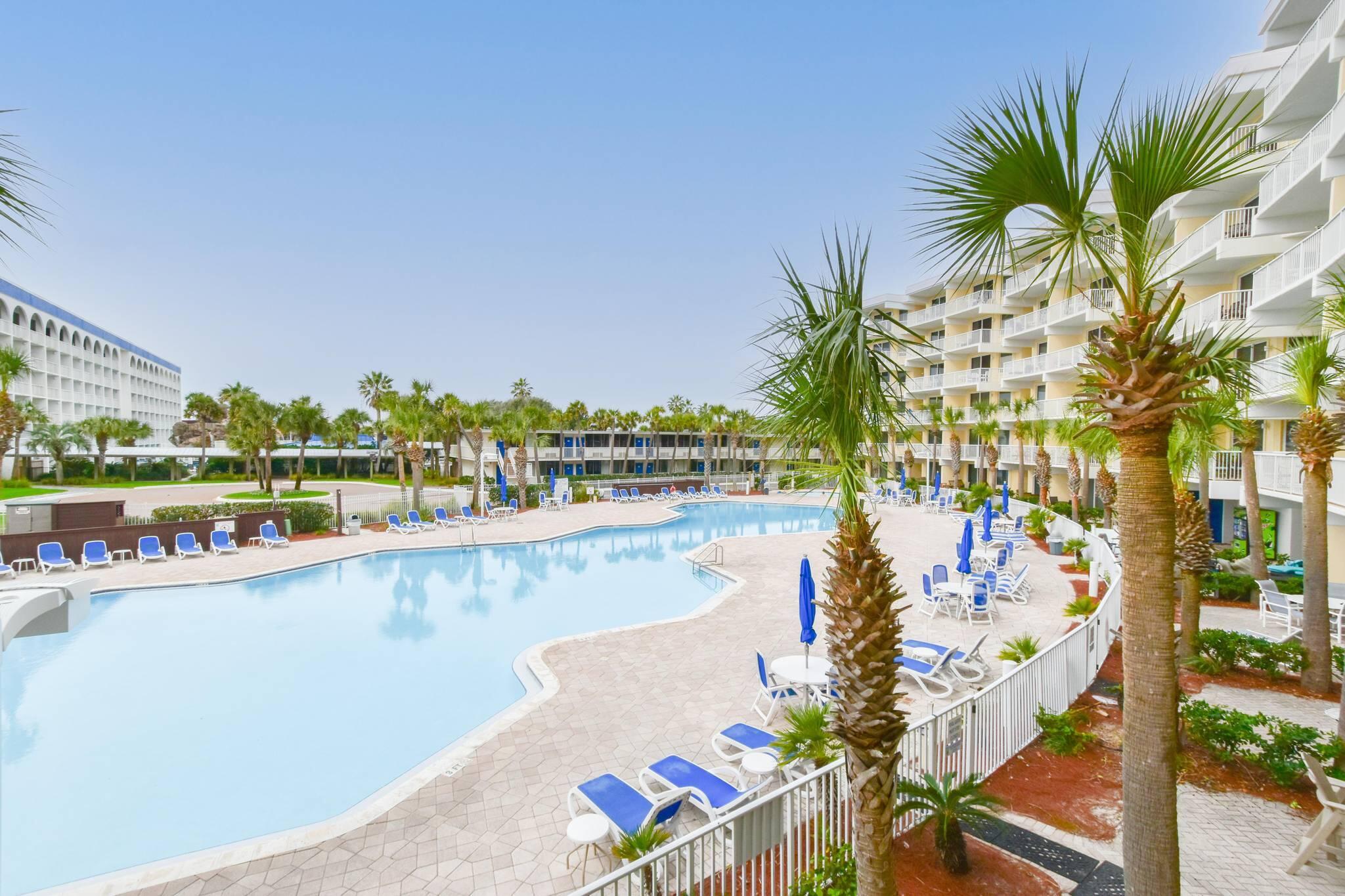 Expansive pool area surrounded by palms, perfect for sunny afternoons.