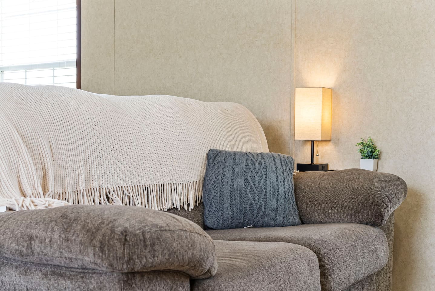 Plush sofa with soft throws and warm lighting, creating a welcoming and comfortable atmosphere.