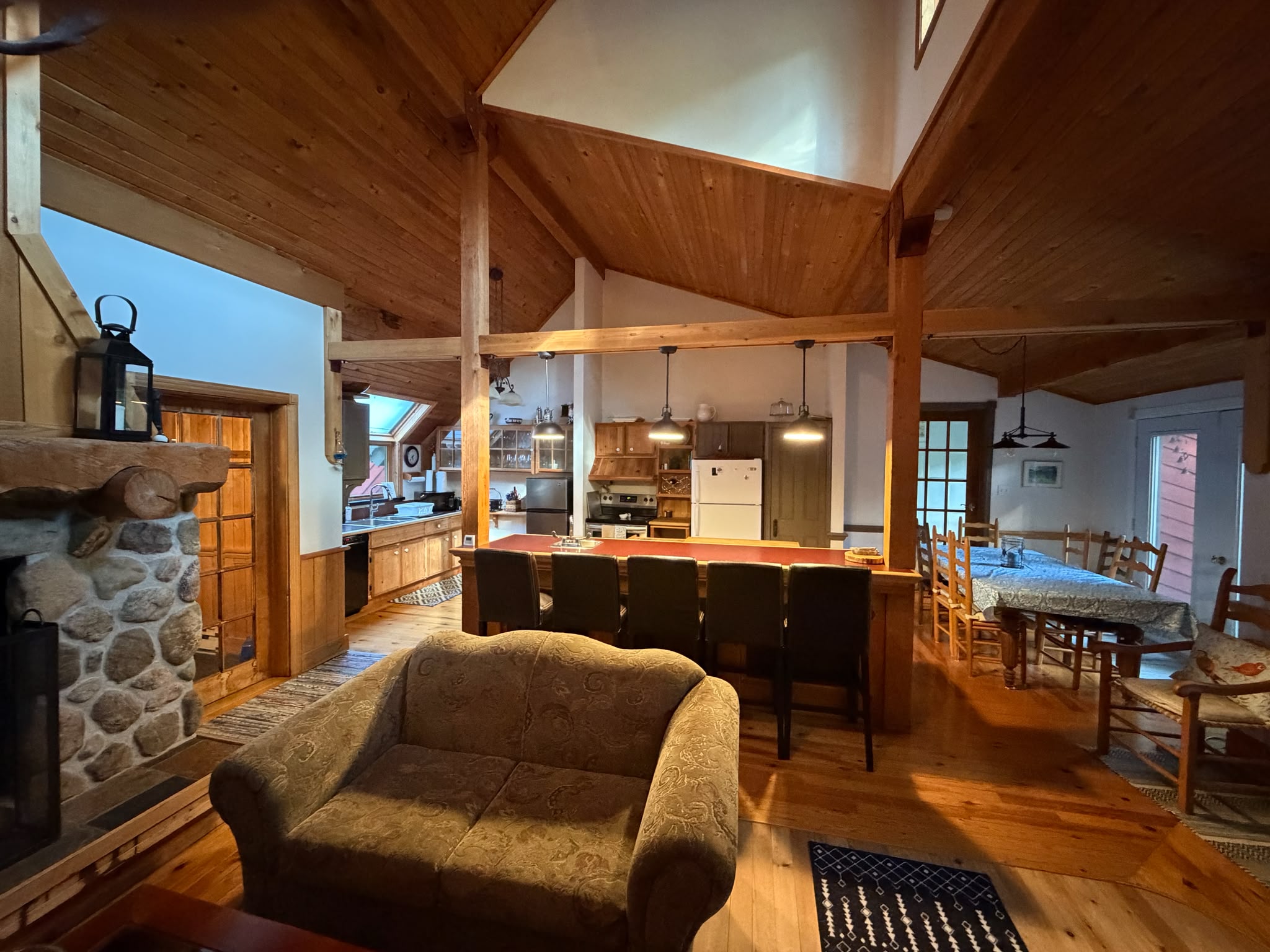 In front of fireplace with kitchen and dining area at other end of room