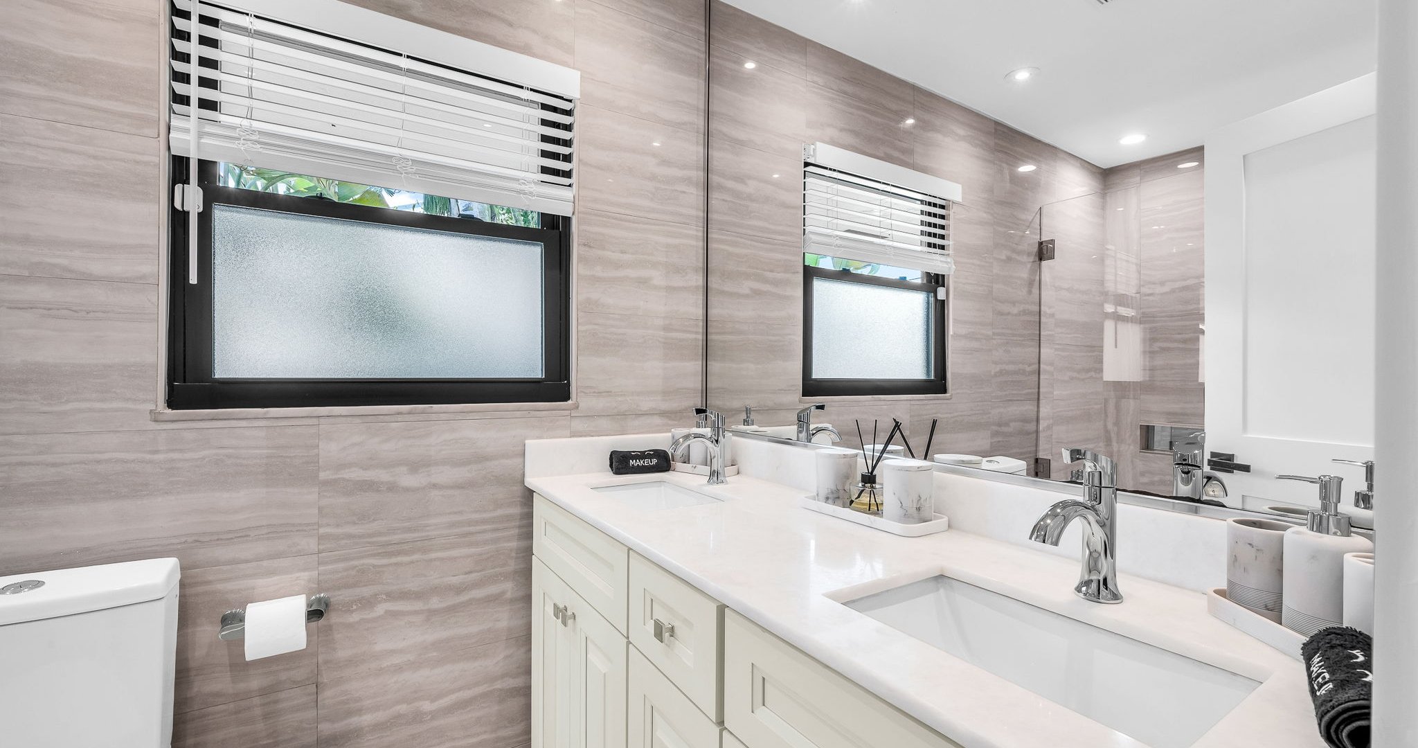 The ensuite bathroom features a sleek double vanity, elegant stone finishes, and a spa-like shower/tub combo with glass enclosure. Designed for both style and comfort, it’s the perfect space to refresh and unwind