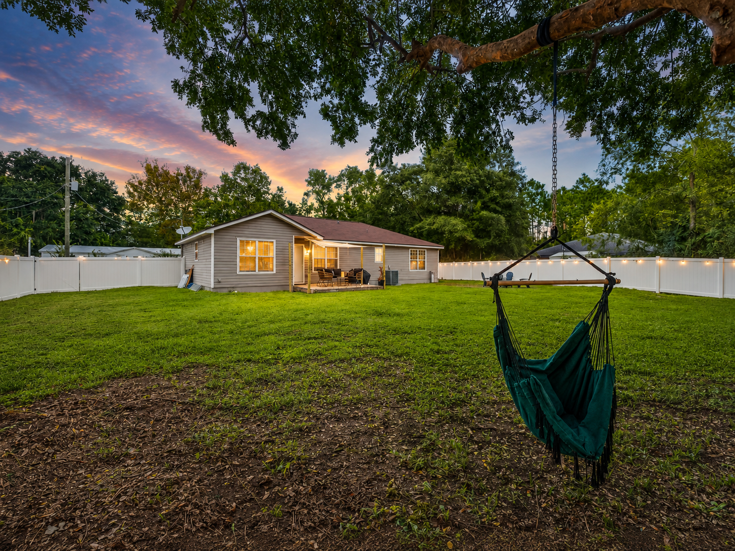 Spacious backyard with hammock chair, sunset views, and cozy patio retreat.