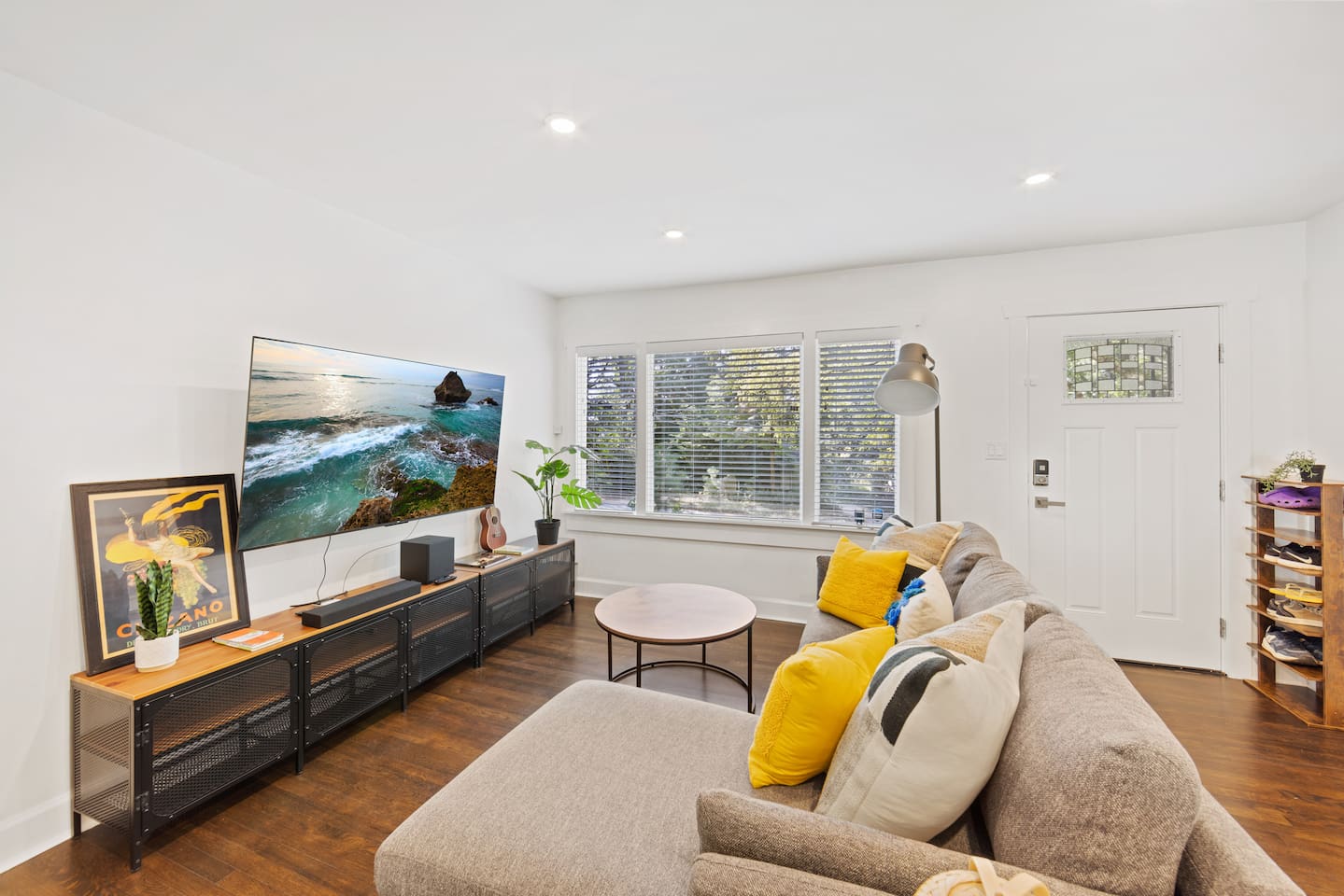 Living room with 70" smart TV and chaise lounge couch.  Large south facing windows let in a lot of natural light.