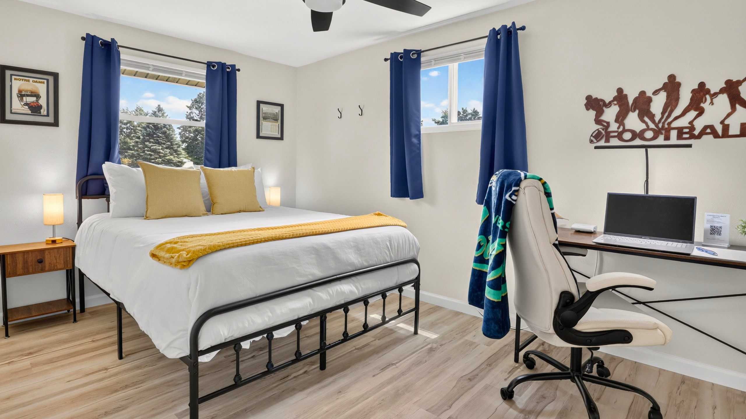 Queen bedroom with a dedicated workspace, ergonomic executive chair, and subtle Notre Dame touches.