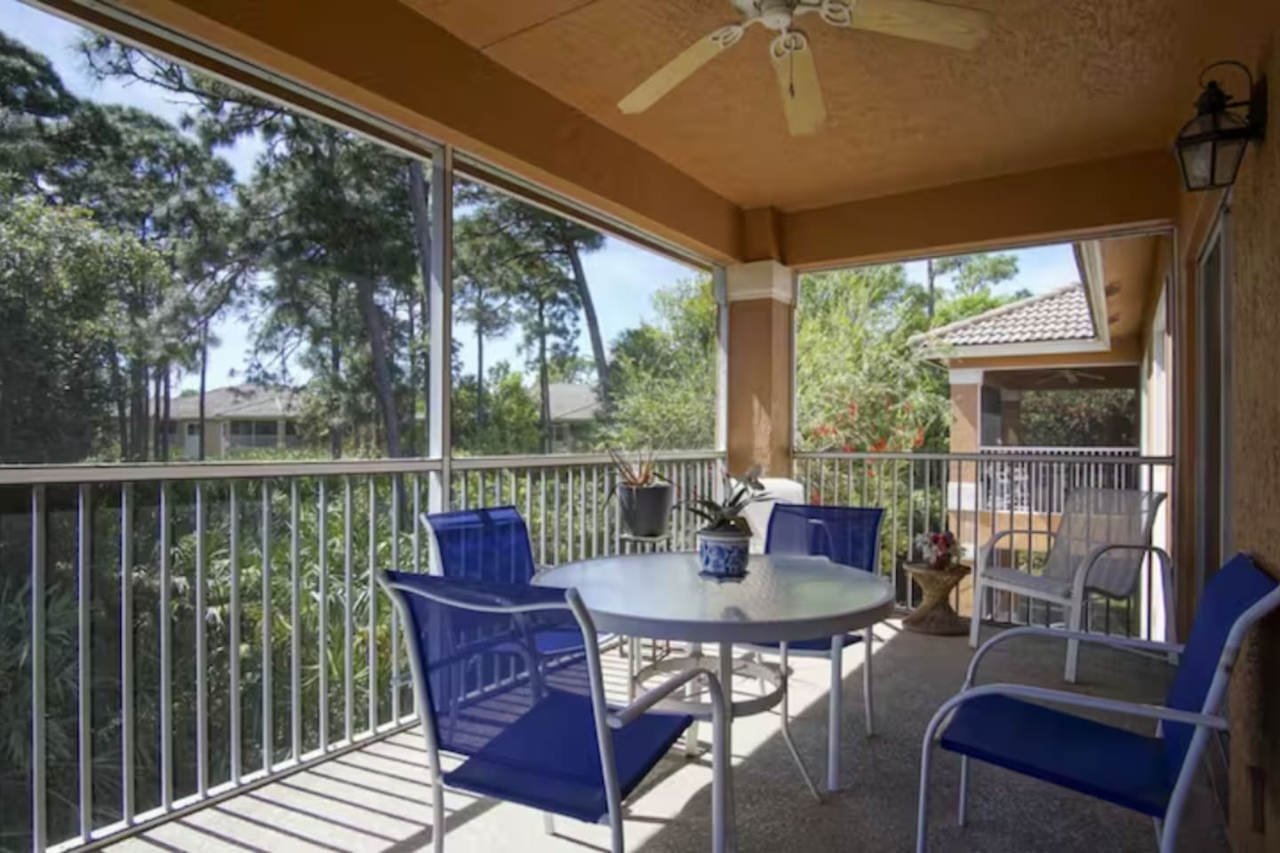 Spacious screened balcony with seating, ceiling fan, and relaxing views of the landscaped surroundings.