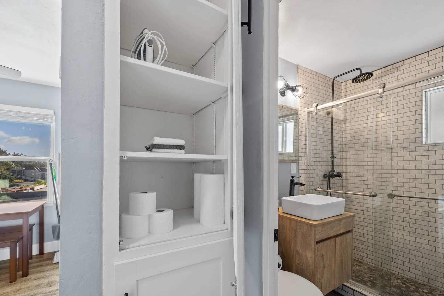 The drawer storage positioned between a modern full bathroom and a cozy dining table. This stylish feature enhances organization while providing easy access to essentials, seamlessly connecting the two spaces for a functional and inviting atmosphere.
