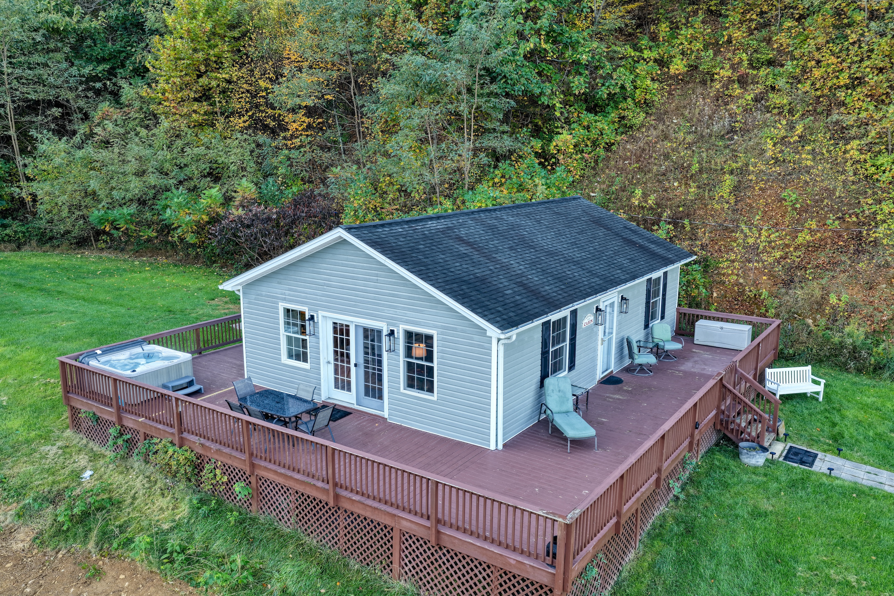 A view of the expansive decks with hot tub, dining, lounging, and a grill around back. Fun fact: we have more deck square footage than house. Priorities!