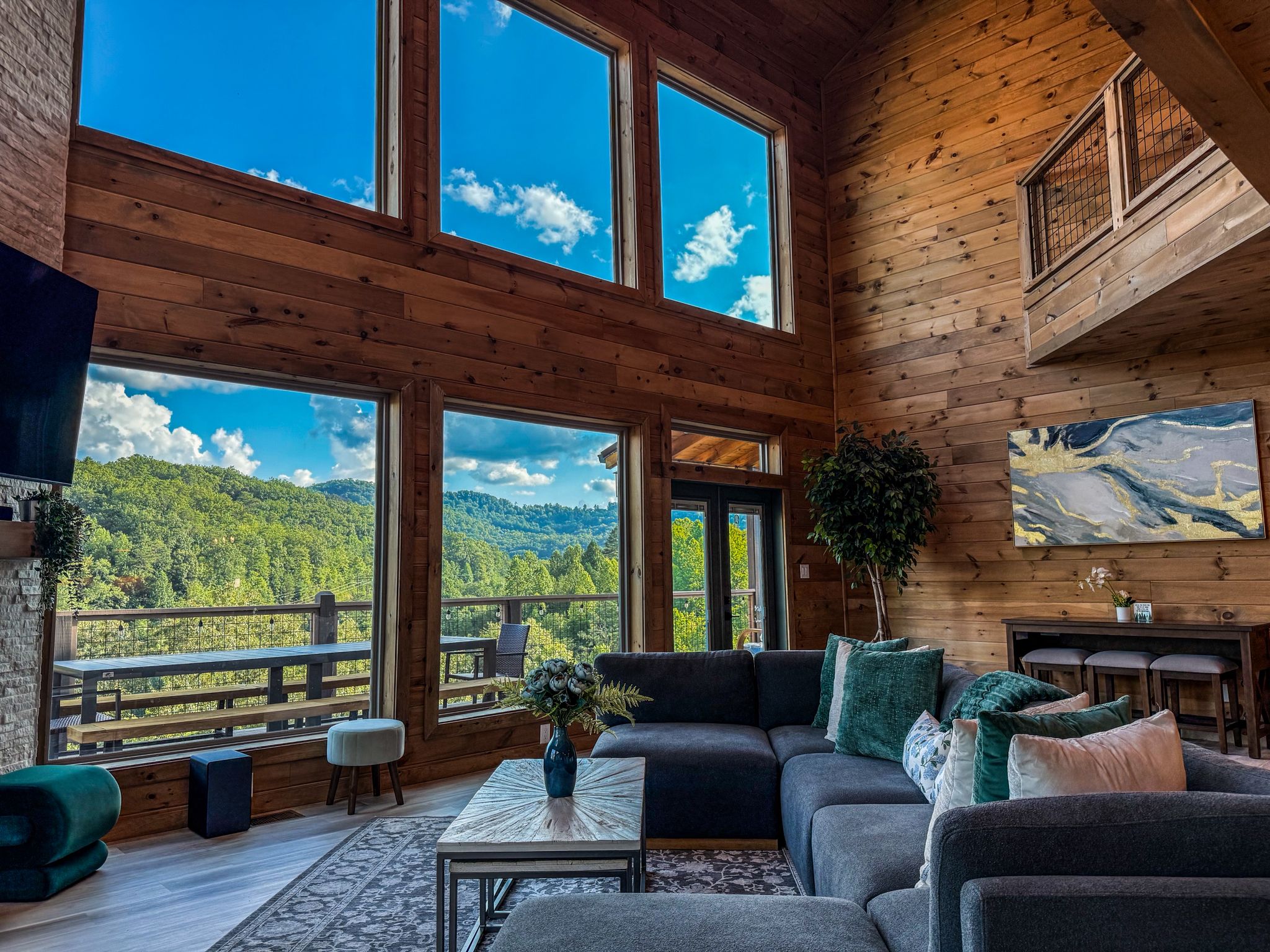 Soaring ceilings, warm wood walls, and wall to wall windows frame sweeping mountain views in this inviting great room. Cozy seating, natural light, and peaceful scenery set the tone for slow mornings and fireside evenings.