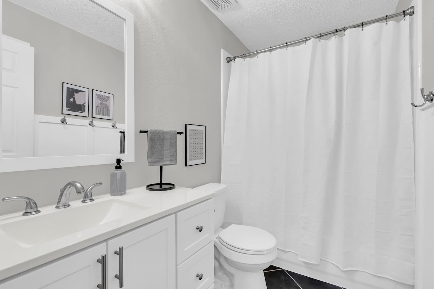 Clean and spacious bathroom offering a combo tub and shower, vanity, modern finishes, and plenty of space for getting ready.