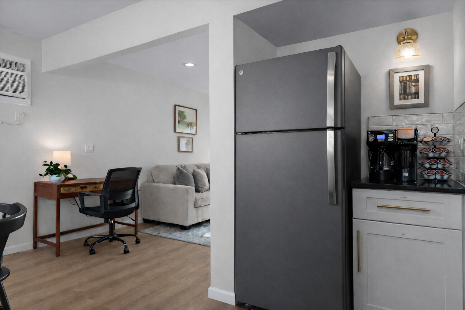 Thoughtfully designed kitchen corner with coffee station and modern appliances, flowing seamlessly into the living area and dedicated workspace.
