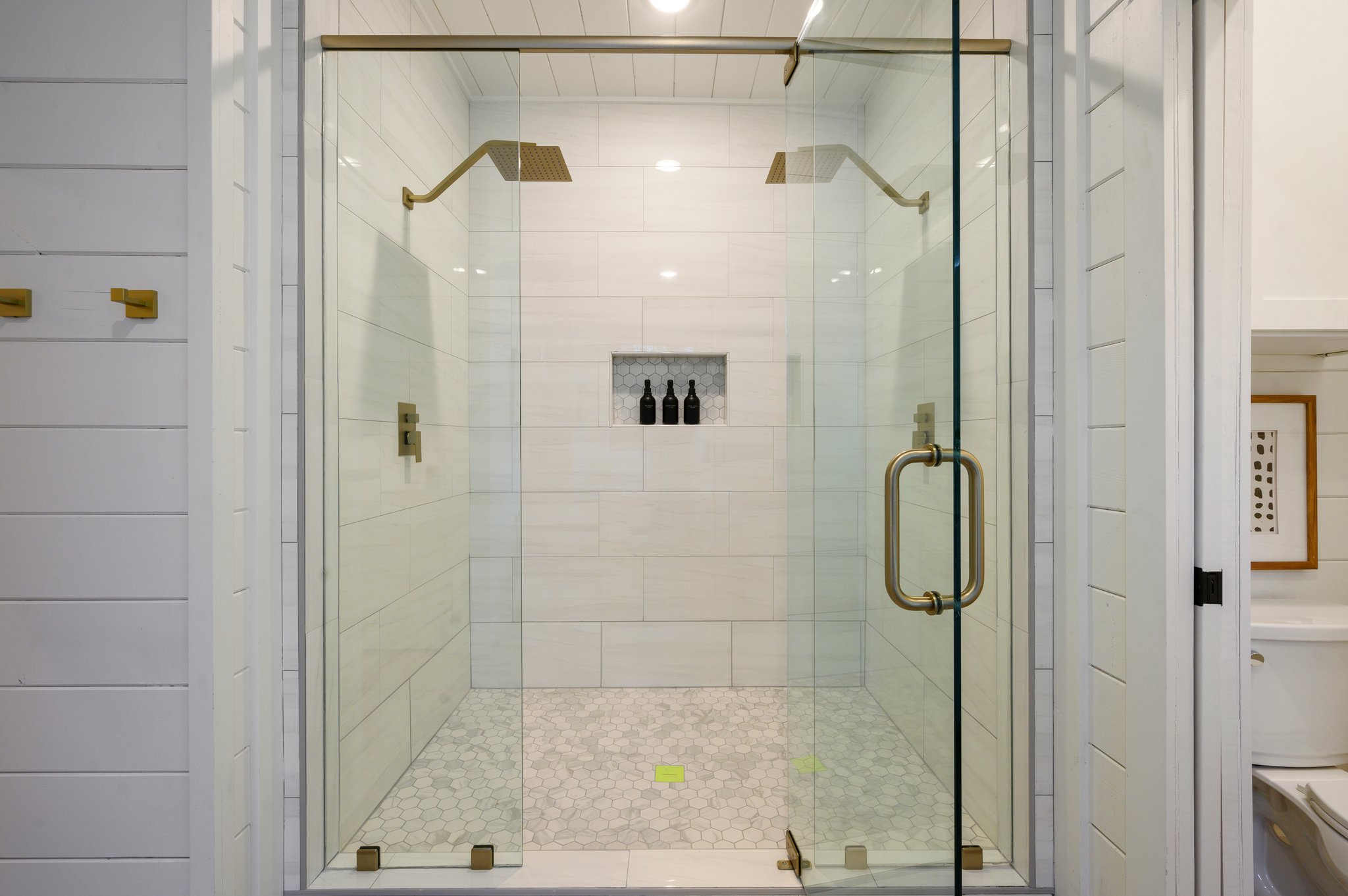 A spacious glass walk-in shower with dual rainfall showerheads offers a luxurious experience.