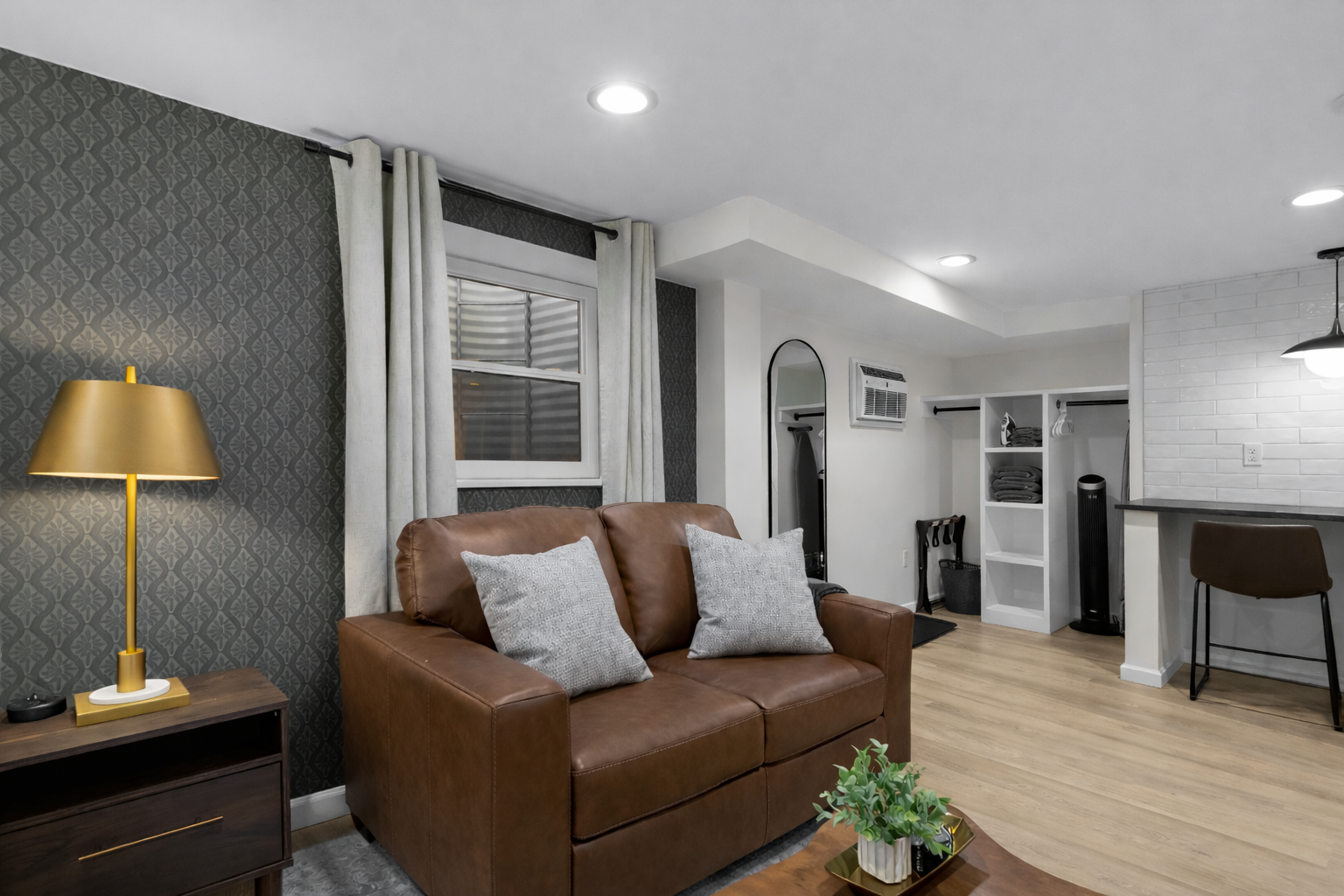 Spacious studio living area with cozy leather seating, warm lighting, and an open flow into the kitchen—perfect for relaxing, dining, and enjoying your stay.