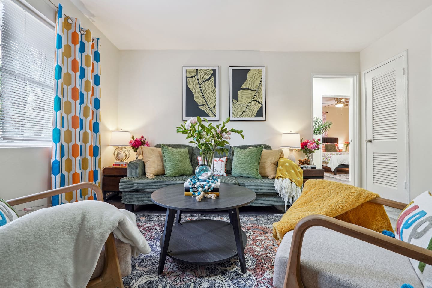 Enjoy a cozy living room featuring a long comfortable sofa, a TV for your entertainment, a ceiling fan, two chair, and a window with a lovely view outside — perfect for relaxing and unwinding.