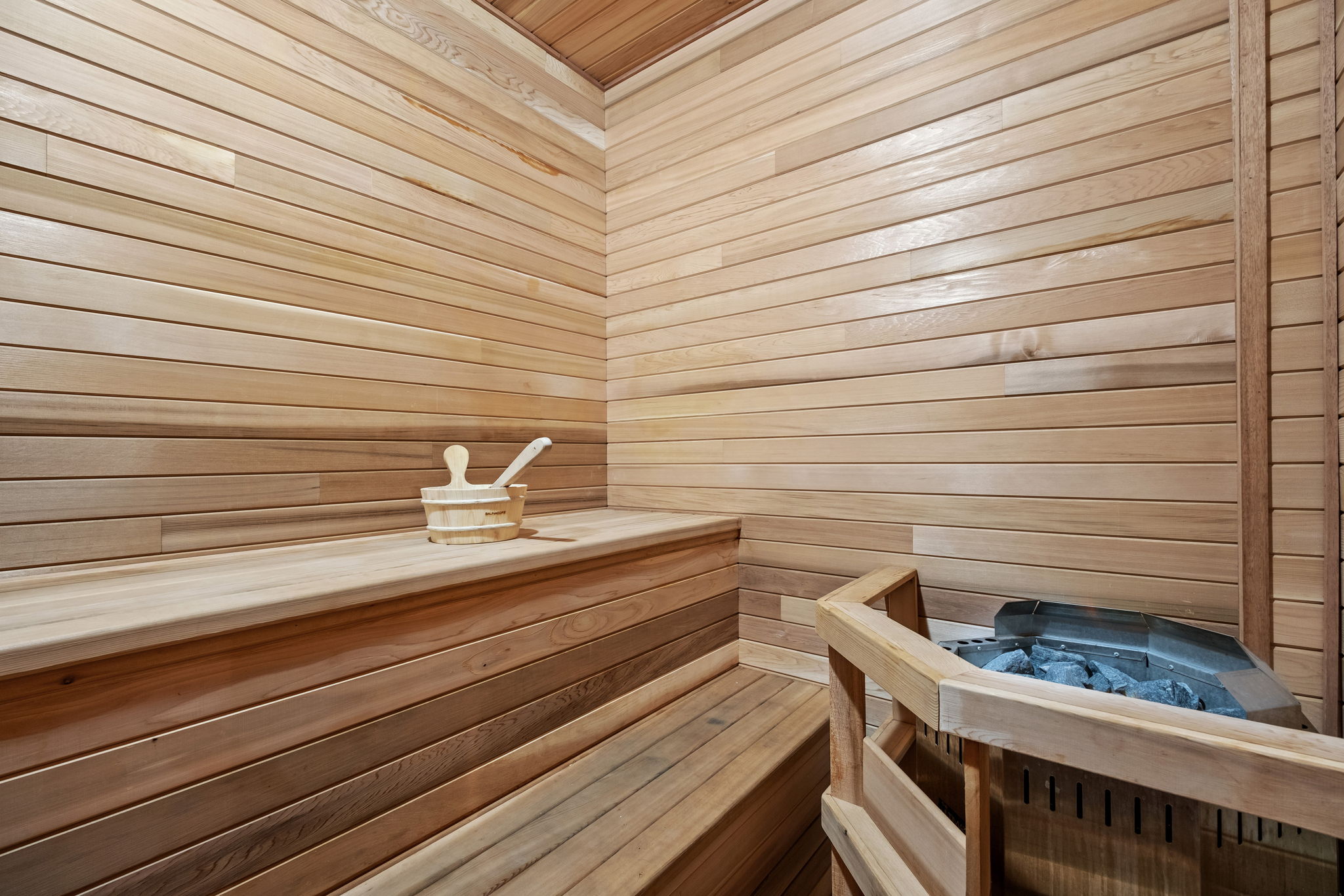 Beautiful indoor Finnish-style sauna with multi-level cedar benches and a powerful electric heater — ideal for relaxation year-round.