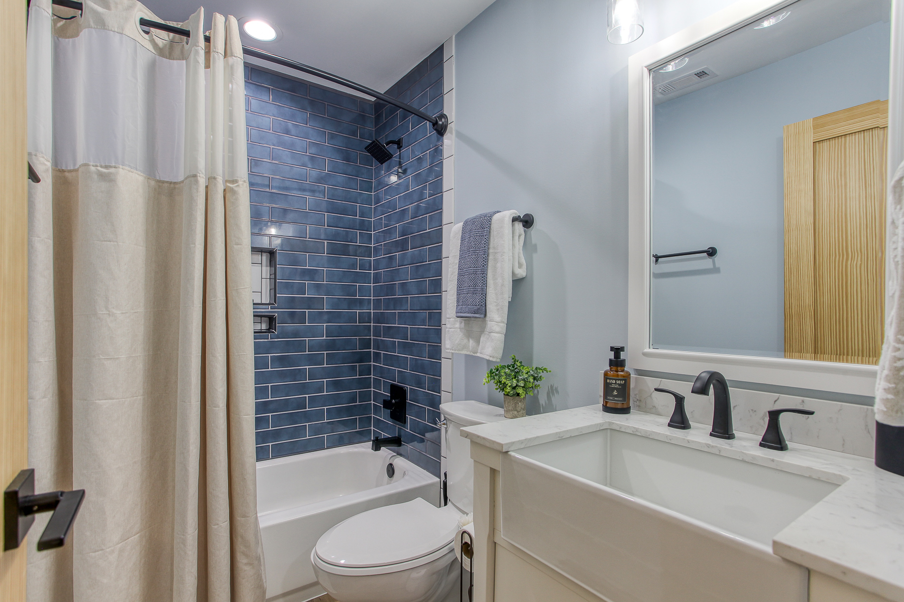 The shared upstairs bathroom at Robbin’s Nest on Snowbird Creek features a tub-and-shower combination with blue tile and a spacious vanity.
