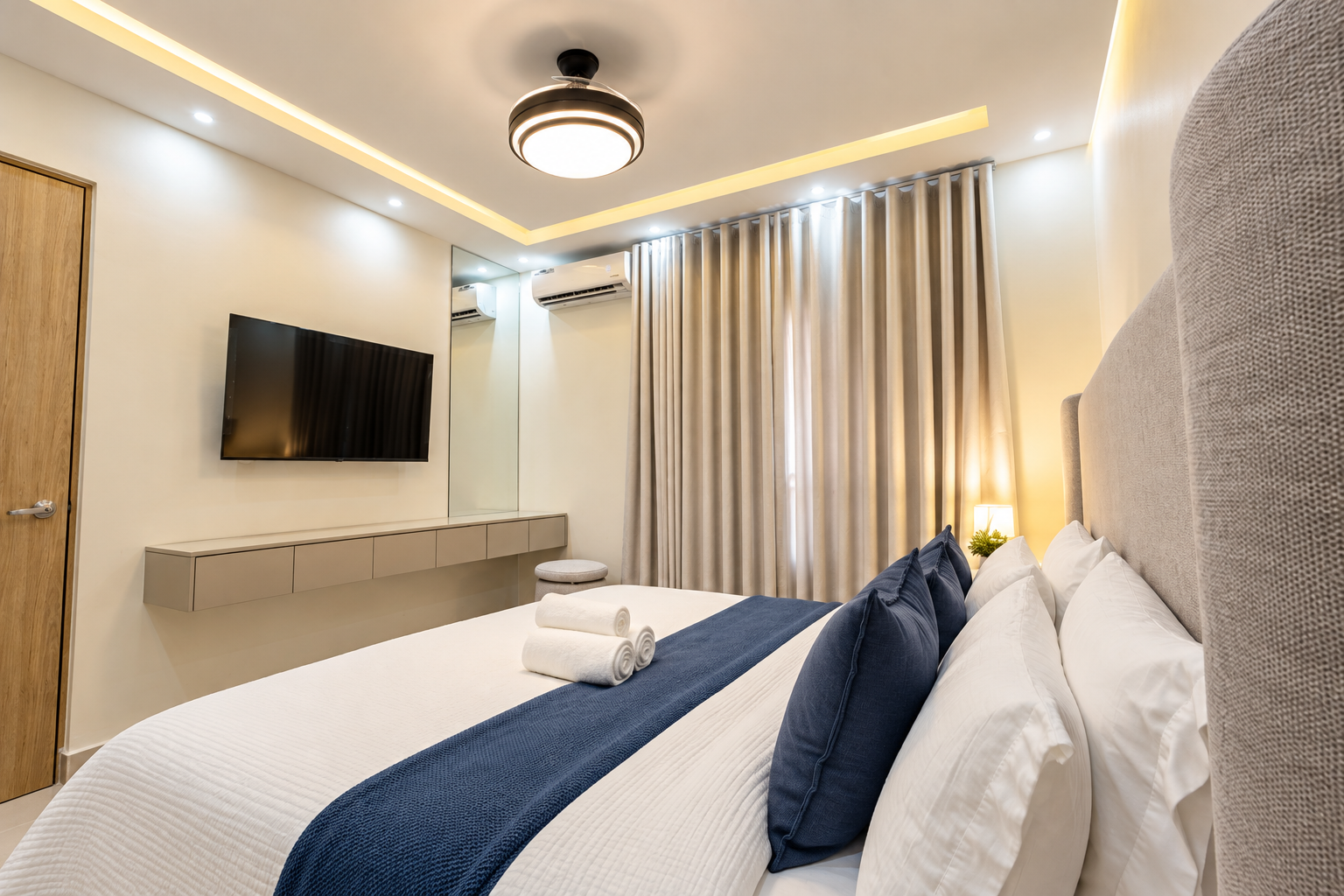 Spacious primary bedroom with a king bed, A/C, ceiling fan, TV, and vanity/workspace. 🛏️✨