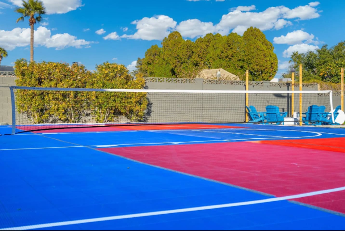 A full pickleball  court adds even more room to play, framed by lush greenery and blue Adirondack chairs for anyone cheering from the sidelines.
