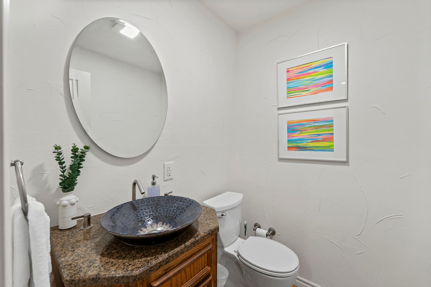 Half bath featuring a statement vessel sink, colorful art, and designer details.