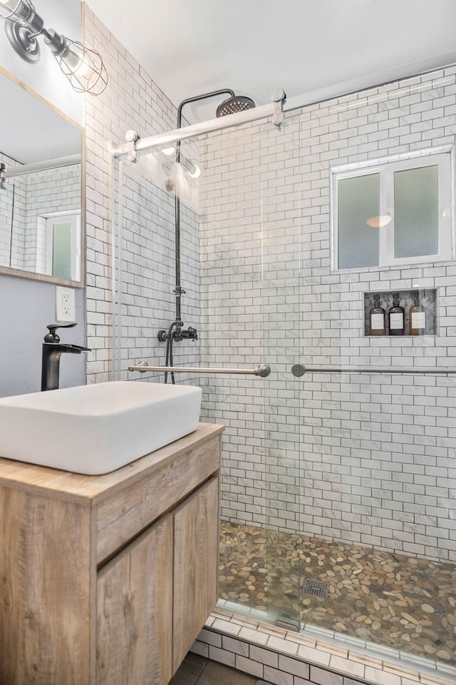 Elegant full bathroom showcasing a sleek glass door shower, a stylish sink, and ample drawer storage. A large mirror adds a touch of sophistication, reflecting light and enhancing the space's airy feel. Perfect for relaxation and everyday routines.