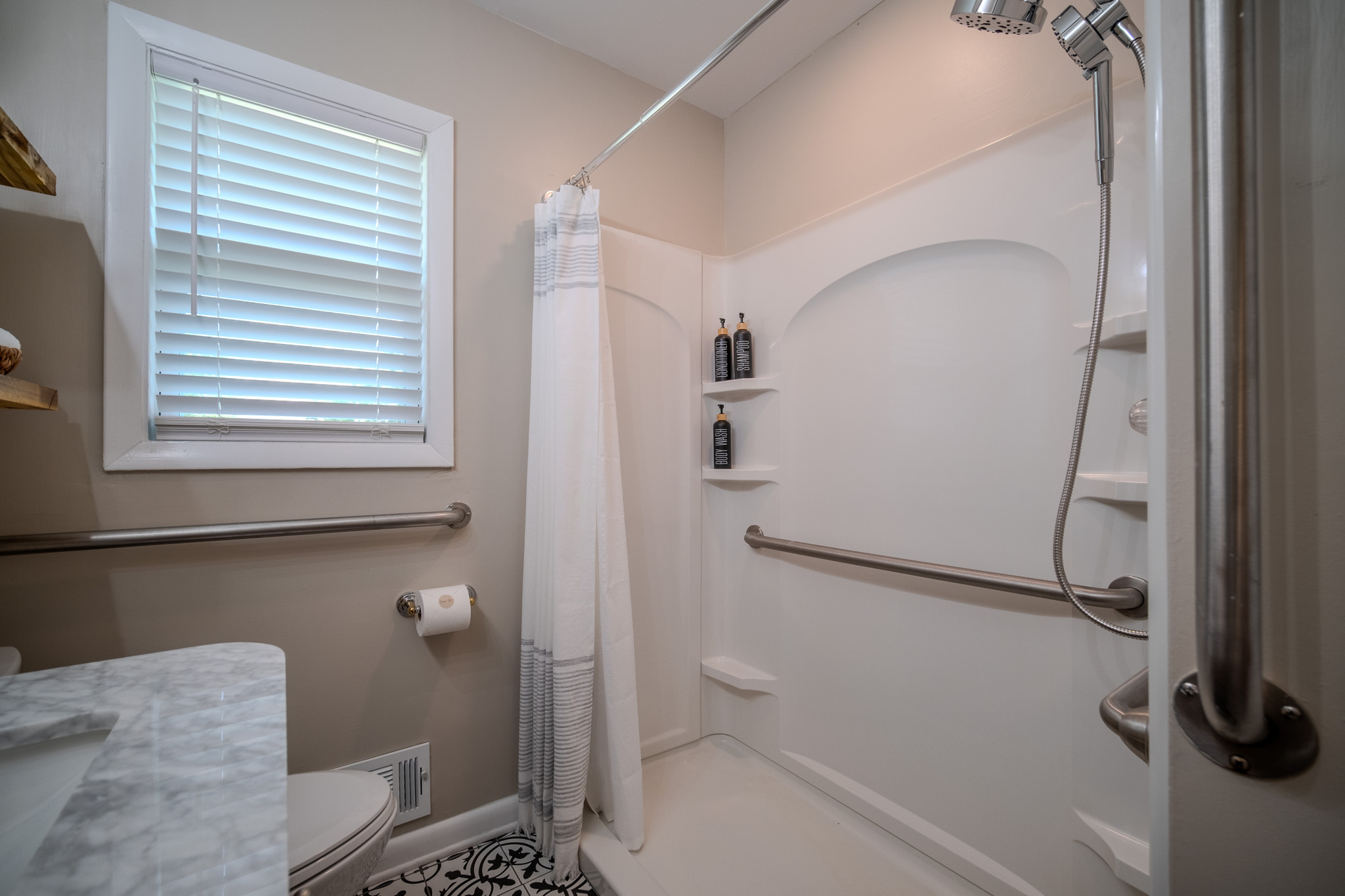 Spacious walk-in shower stocked with shampoo, conditioner, body wash, and fresh towels.