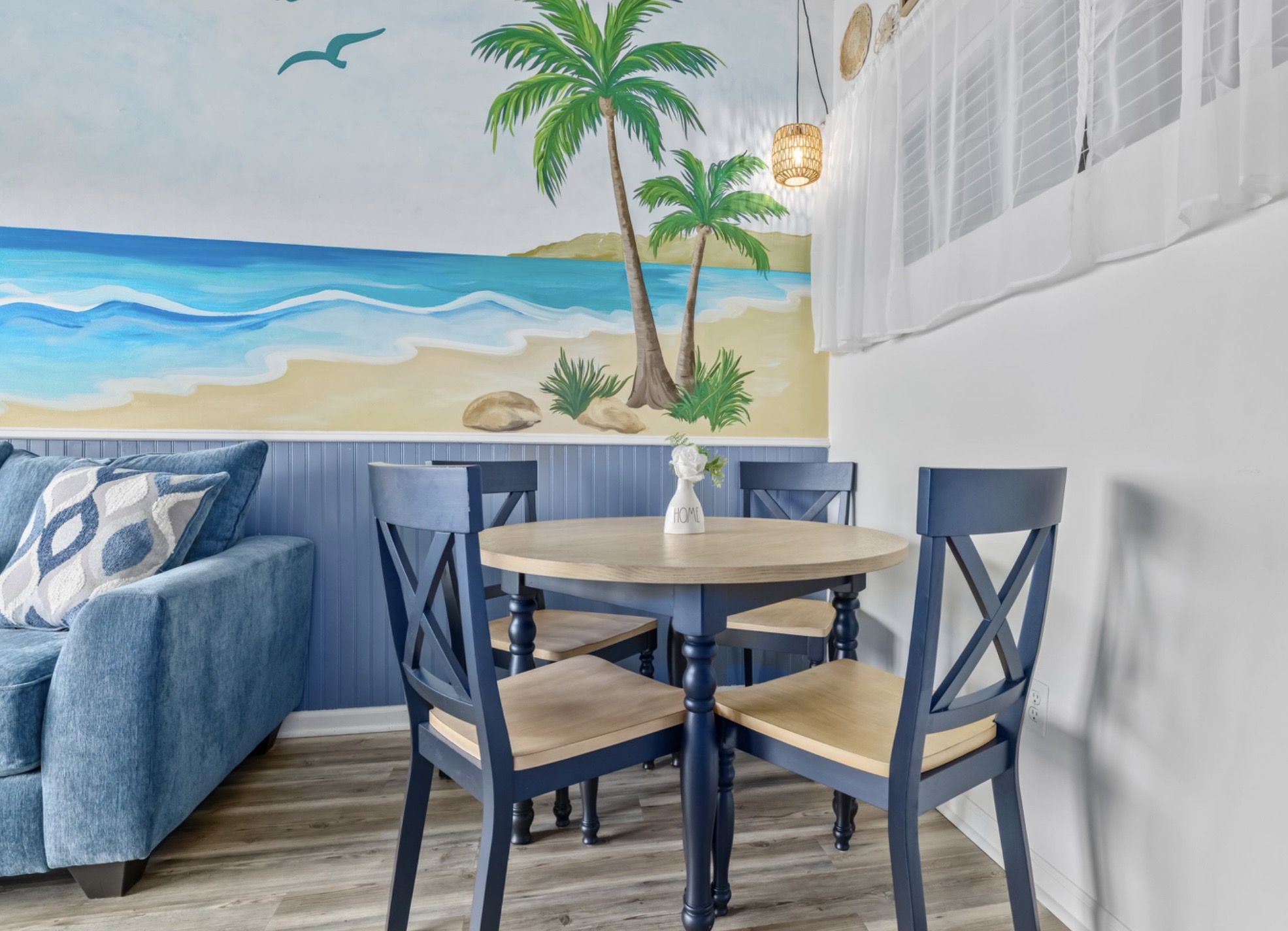 Gather, dine, reconnect 🍽️
A cozy dining space set against a hand-painted coastal mural. Perfect for morning coffee, takeout nights, or family meals after a sun-soaked beach day.