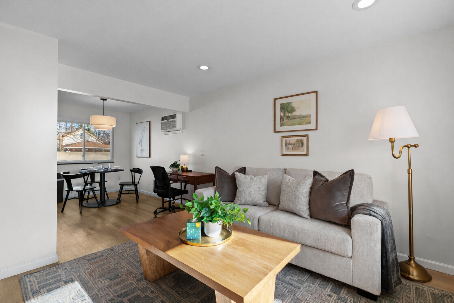 Comfortable, sunlit living space with plush seating, warm wood accents, and an open layout that flows seamlessly into dining and work areas.