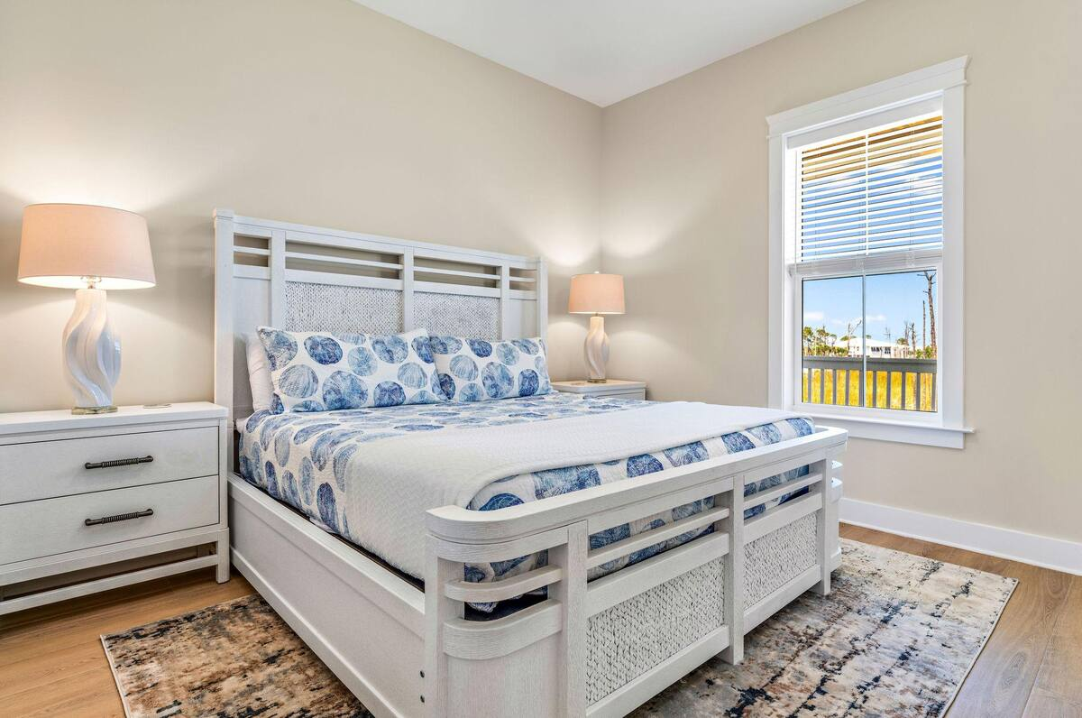 King Bedroom #2 offers a bright and inviting retreat with large windows, coastal-inspired decor, and a 50" Roku TV for relaxing after a day in the sun