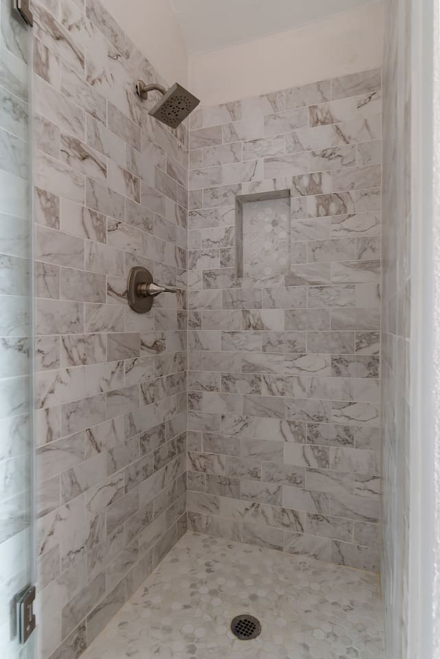Step into this luxurious bathroom featuring a sleek sink and mirror combo, a inviting bathtub, and a spacious walk-in shower. Pamper yourself in style and comfort.