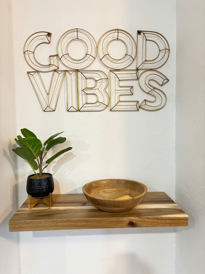 Decorative entry shelf with a small plant, wood bowl, and simple styling that adds a warm arrival touch.