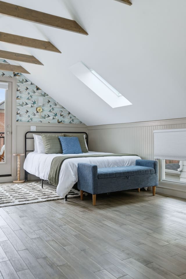 Close-up of one of the queen beds featuring soft linens, accent pillows, and natural light from the skylight above.