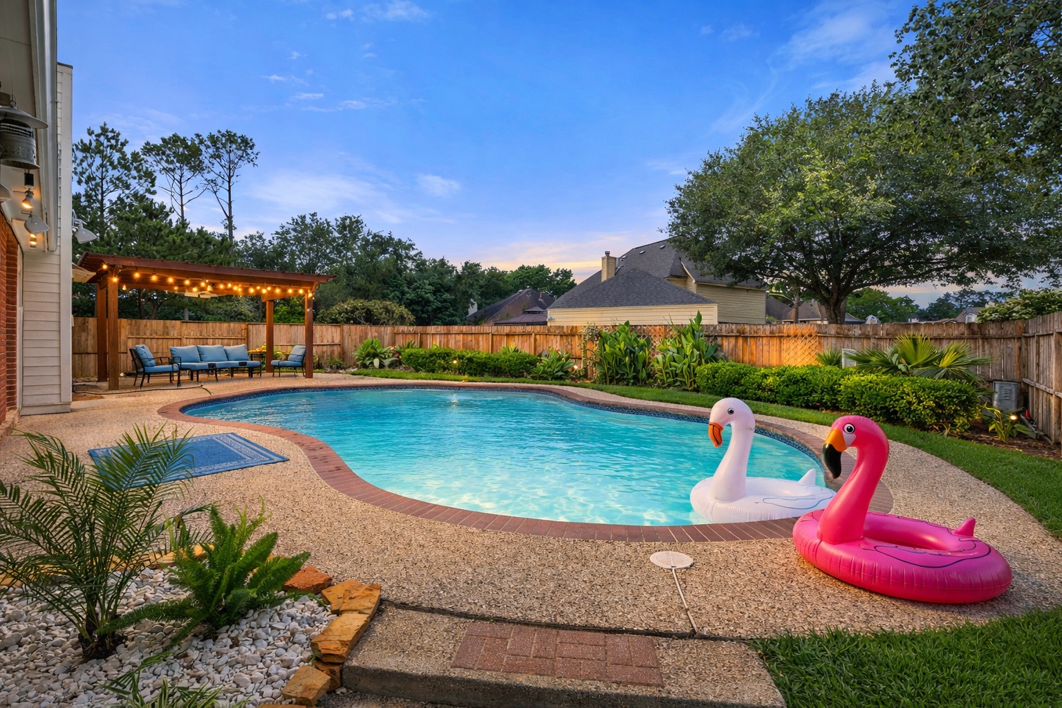 Private backyard oasis featuring a sparkling pool, shaded pergola lounge, and privacy fence — ideal for relaxing or entertaining.