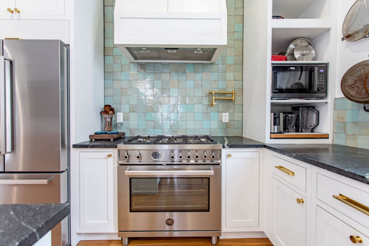 A modern kitchen featuring a stove with an oven, complemented by a built-in exhaust above for ventilation, and equipped with a microwave and blender, creating a fully functional and well-appointed cooking space.