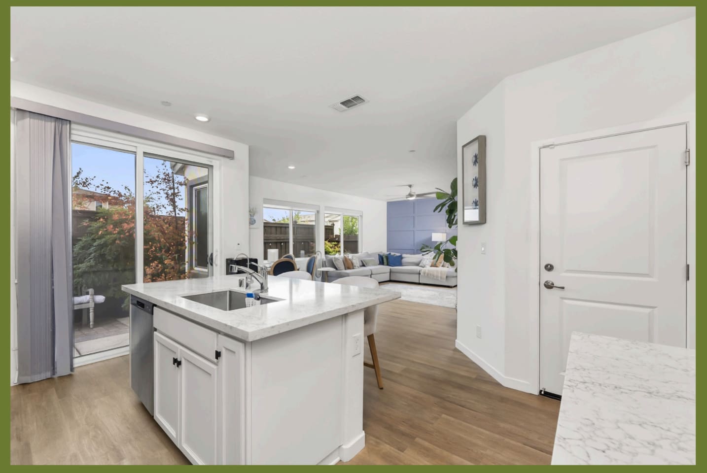 Kitchen island with patio door access, open flow to the living room, and bright natural light throughout the main space.
