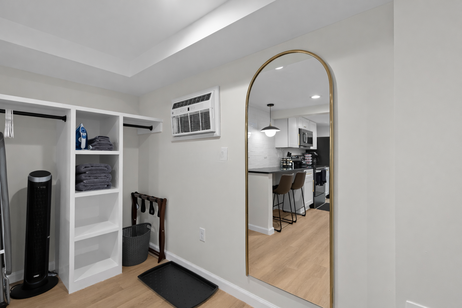 Thoughtfully designed entry space with open storage, fresh linens, full-length mirror, and a seamless flow into the modern kitchen beyond.