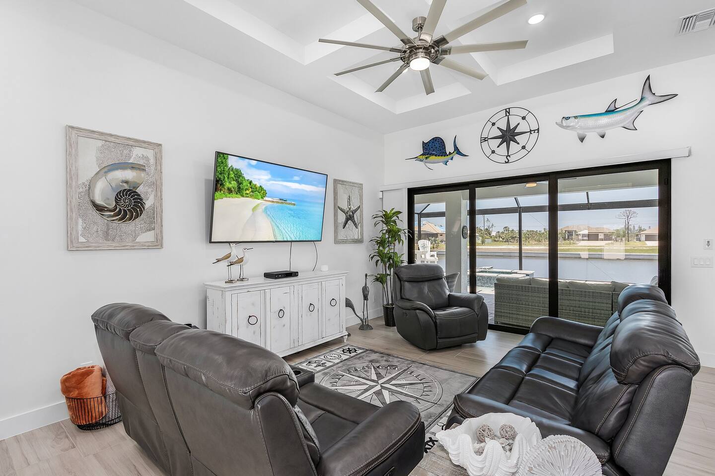 Spacious coastal-designed living room with captivating views of the pool and water, featuring a TV for your entertainment!