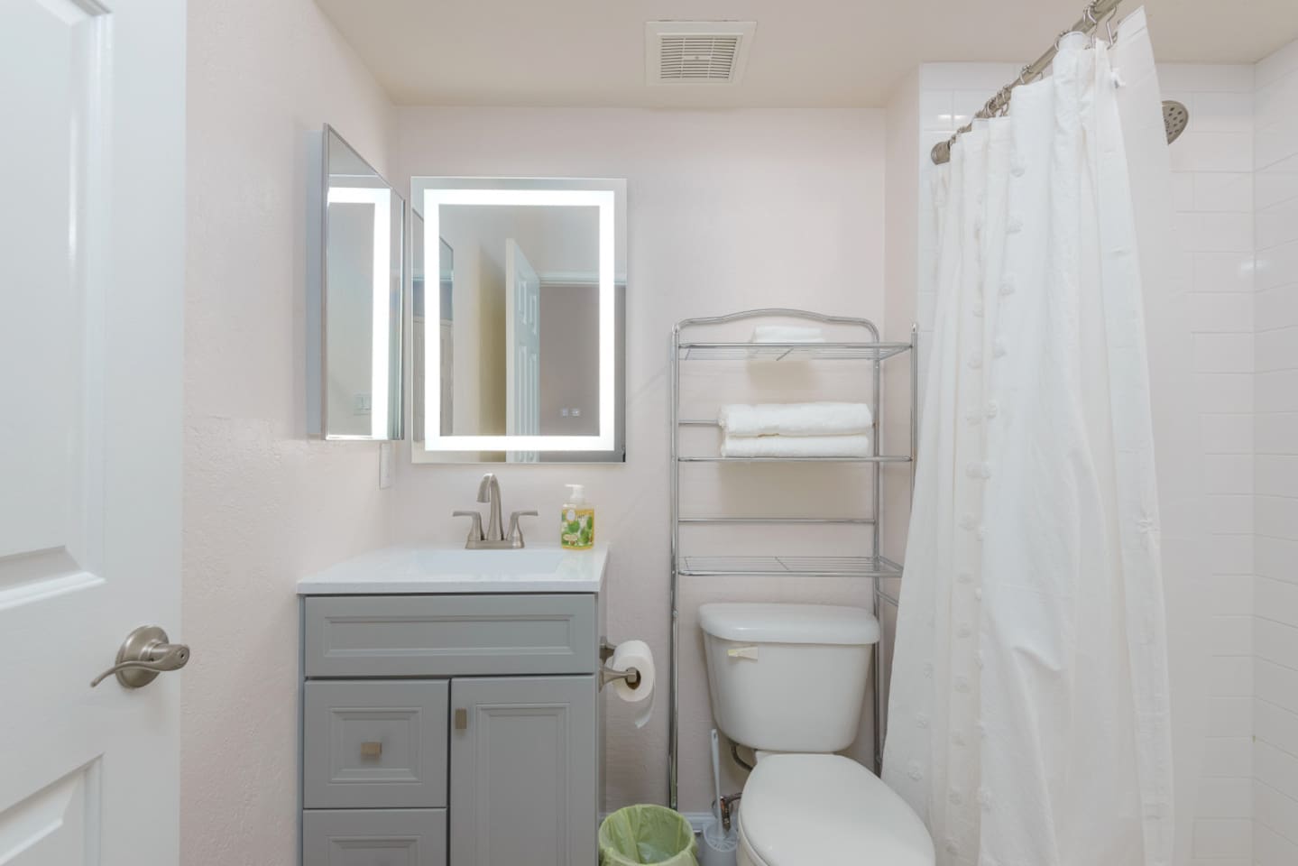 Full bathroom with a shower, vanity storage, fresh towels, and simple essentials for daily use.
