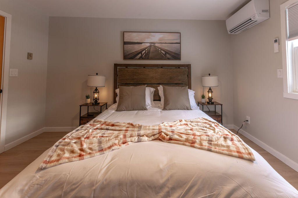 Main level bedroom with a queen sized mattress and side tables. 