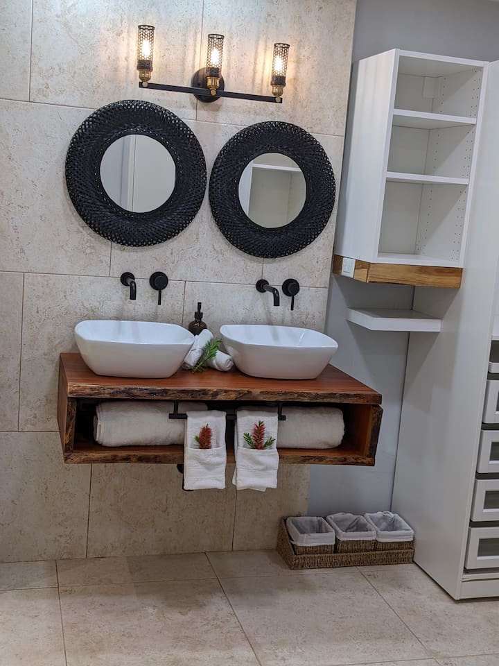 Here is our dual vanities in the primary bath. We made the vanity base out of a single piece of Mahogony. Super fun project and we love the live edge and organic variaton of the lines. 