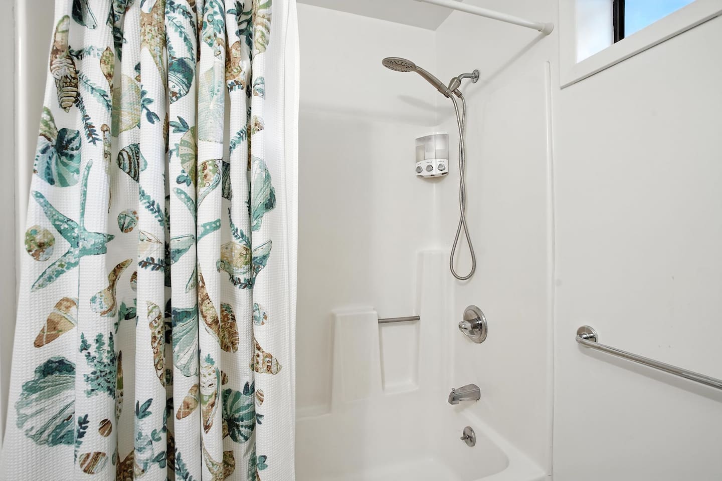 - Fresh white bathroom with tub and shower combination for versatile use  
- Coastal pattern shower curtain adds a fun, decorative touch  
- Includes window for natural light and a clean, bright feel