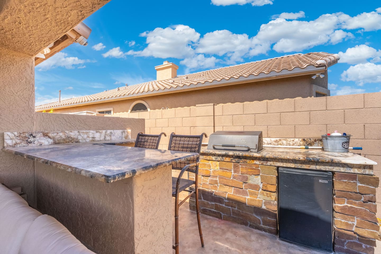 Everything you need for the perfect backyard cookout is right here — a built-in gas grill, granite prep counter, mini fridge, and bar seating tucked into a private corner of the patio.