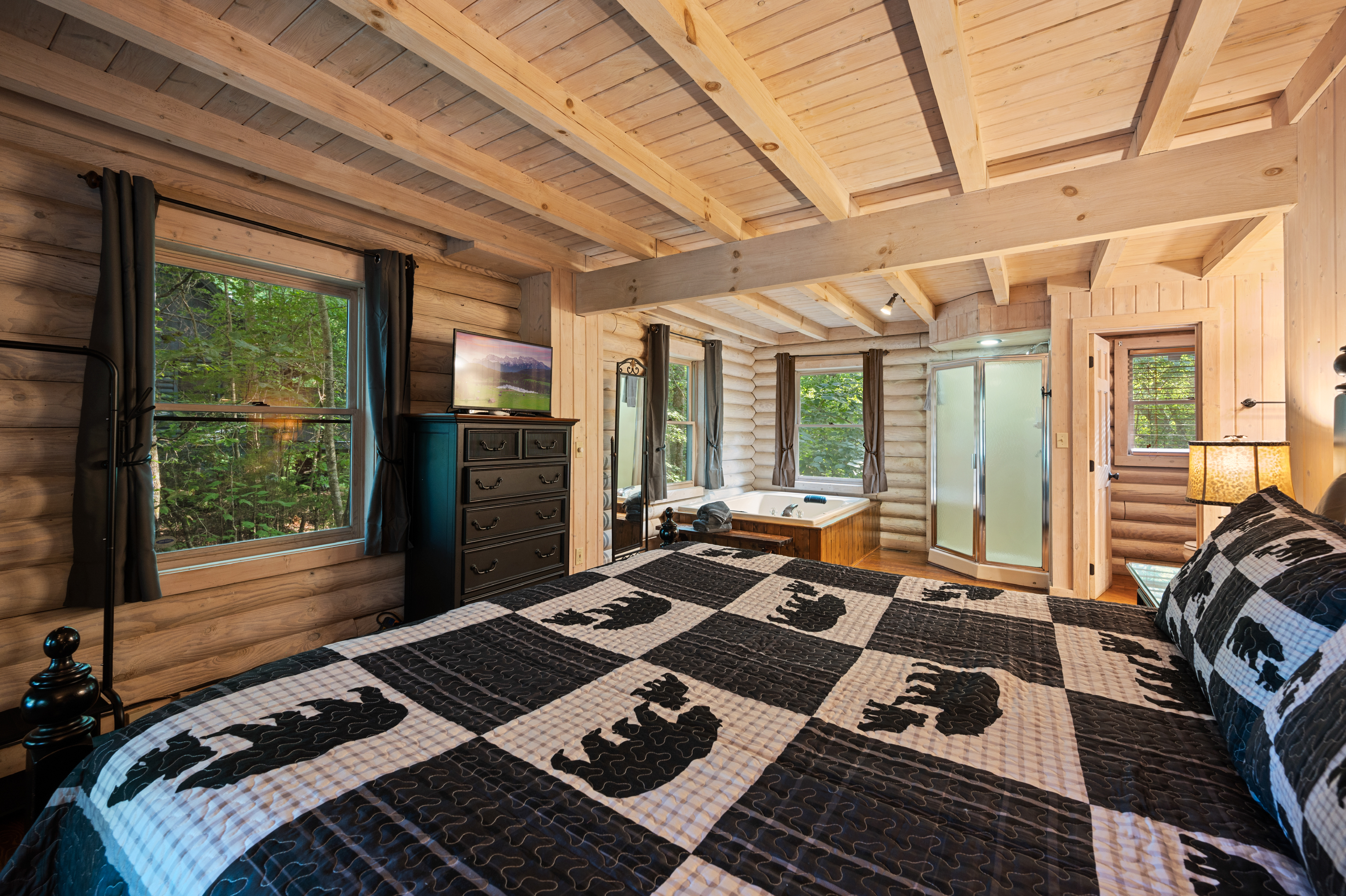 King Suite luxury: jetted tub, shower, TV, & forest views. Your cozy cabin escape!