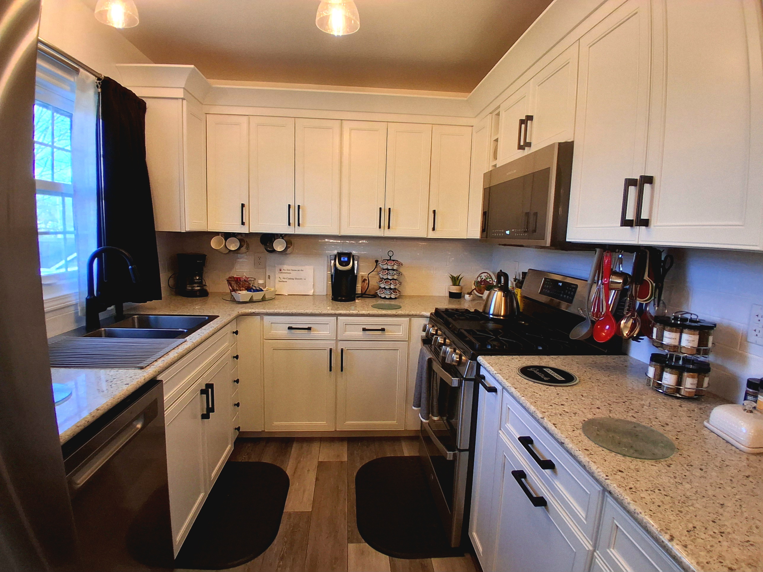 This kitchen features a sparkly peppercorn countertop & generous prep space. It includes two hidden trash cans, a bottle jet dishwasher, XL microwave & a double oven with air fryer & convection baking. The backyard window view is simply dreamy.
