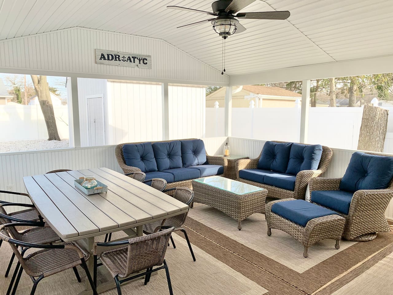 Experience the best of indoor-outdoor living in our screened-in sunroom. Kick back on navy wicker seating to watch the game or enjoy a meal at the large dining table—all while staying protected from the elements in a bright, coastal setting.