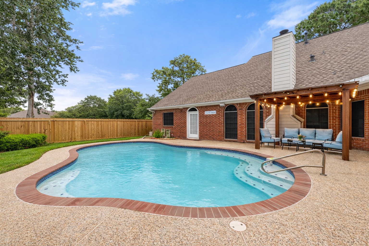 Spacious outdoor living area with a refreshing pool, covered patio lounge, and inviting atmosphere for the ultimate getaway.