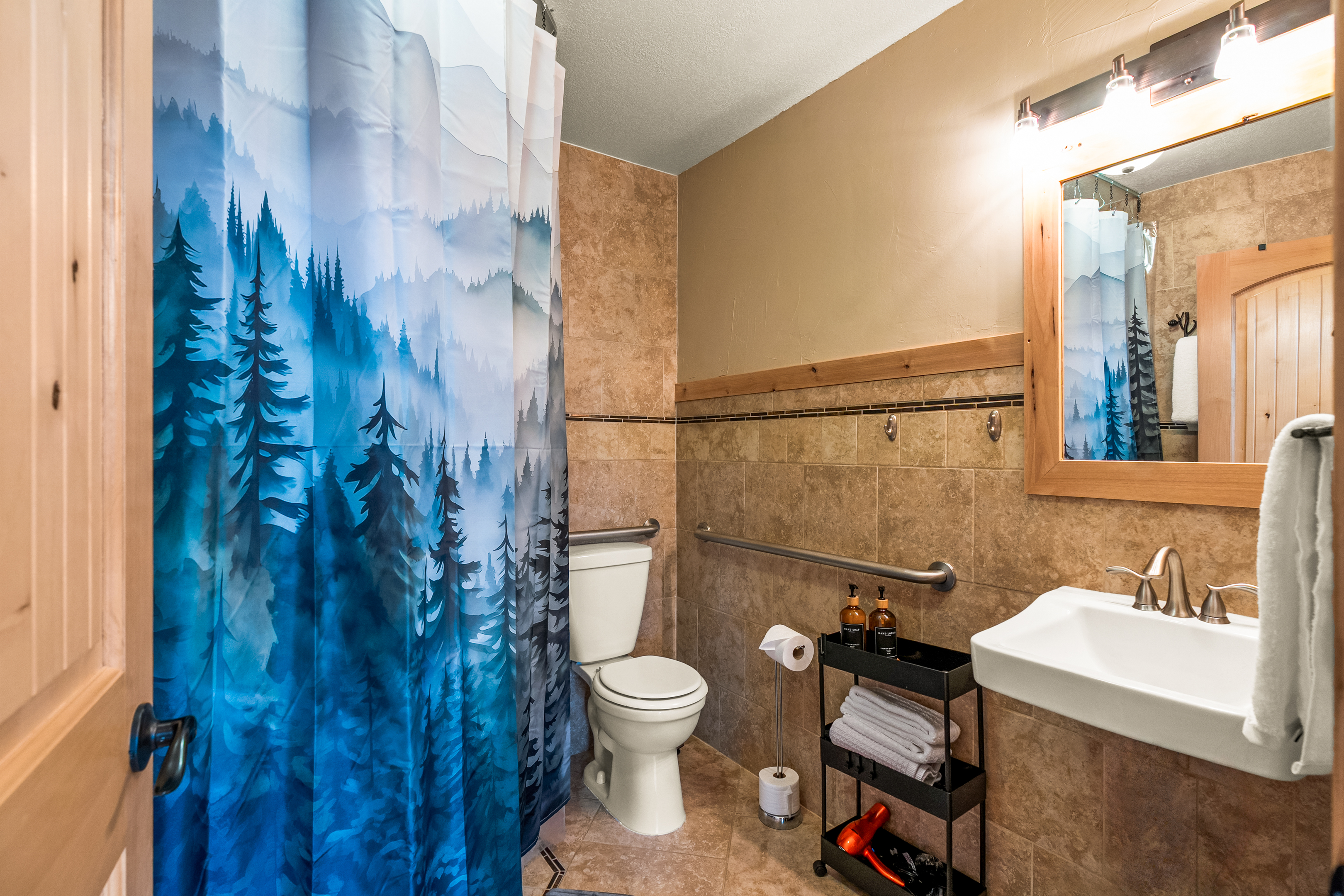 Spacious second bathroom with zero entry shower, grab rails for toilet and wheelchair friendly sink