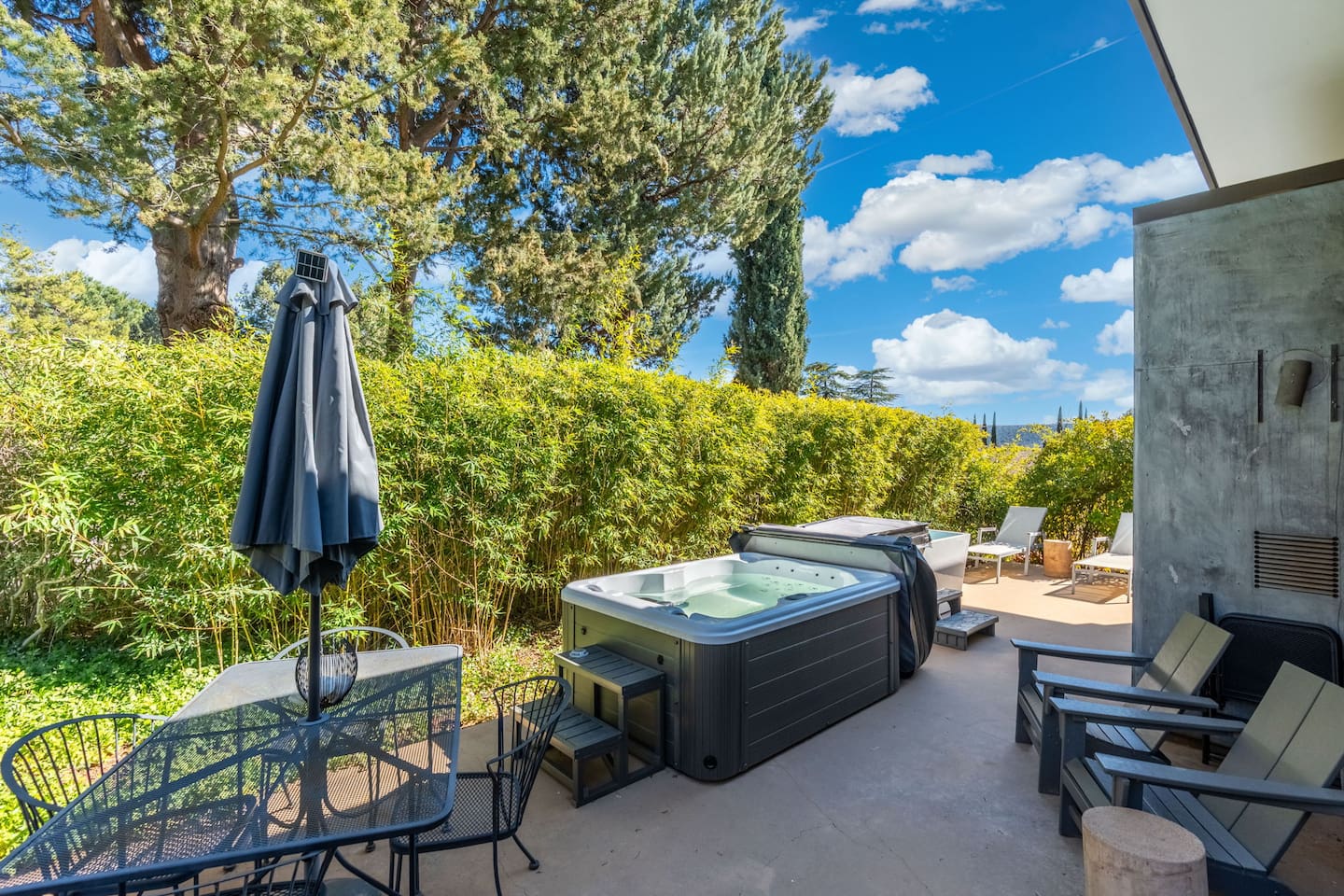 Private patio with hot tub, lounge seating, and lush greenery for a relaxing outdoor retreat.