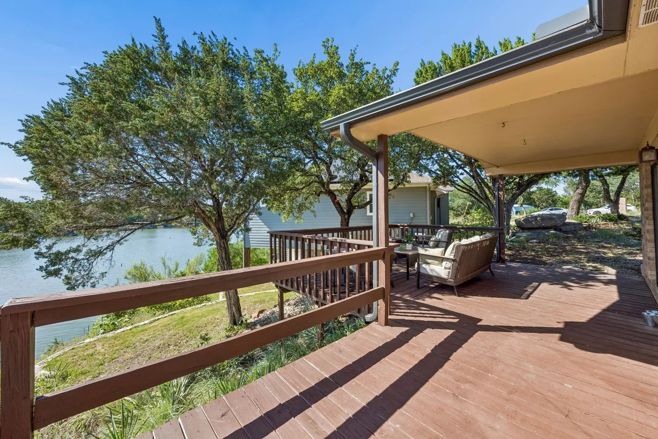 Furnished deck running along the lakeside of the home.