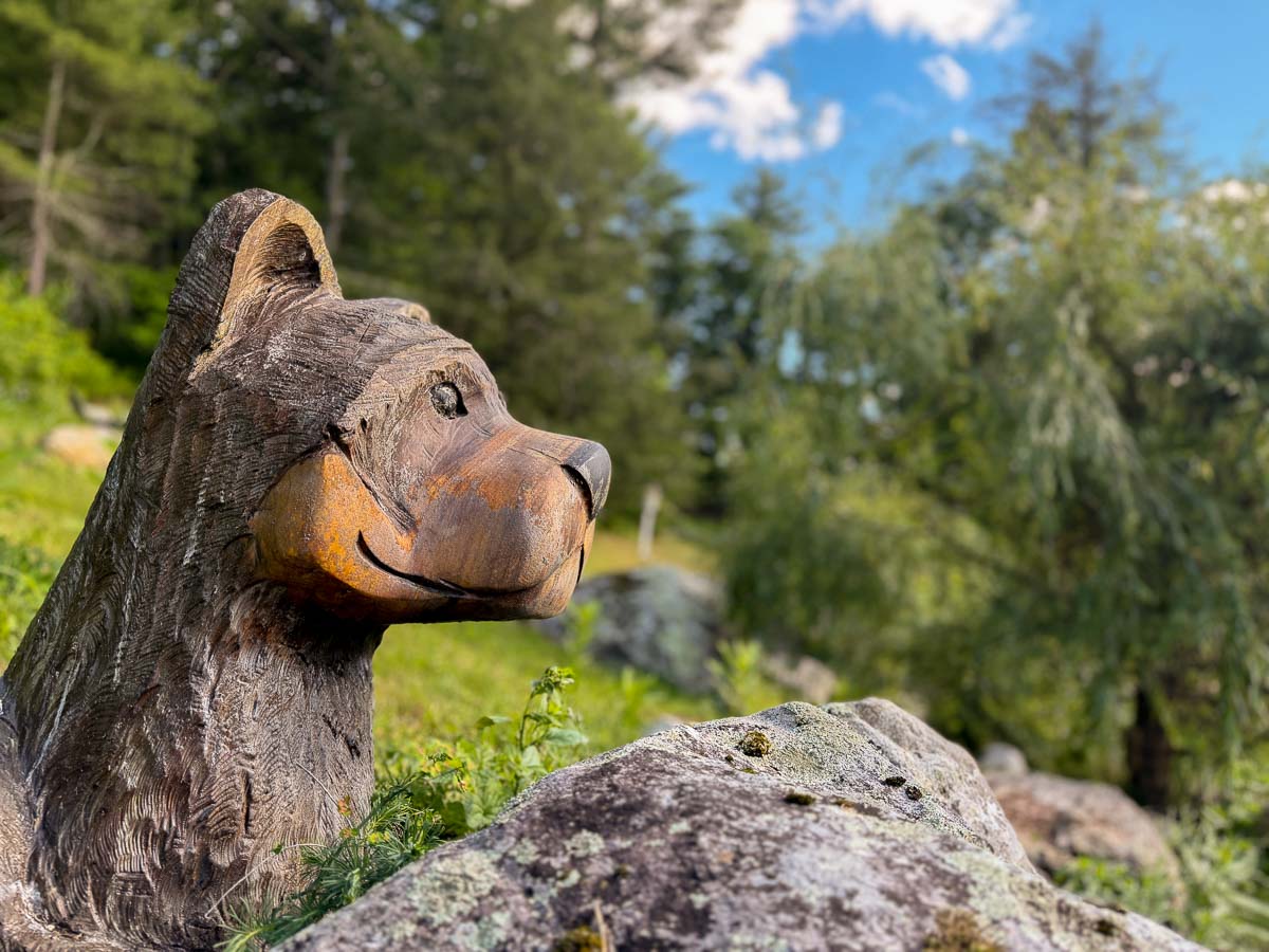 Hand-carved wooden bear on a mossy rock along the summer trail &mdash; Sunset Falls Berkshires