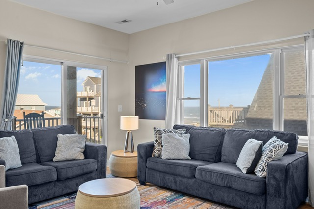 Sliding glass doors and large windows fill the room with natural light and ocean breezes