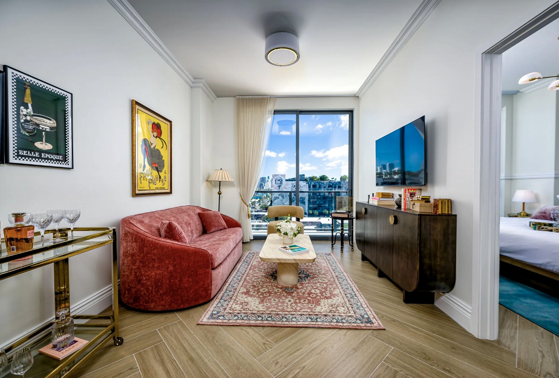 Living room — curved velvet sofa with smart TV and herringbone floors